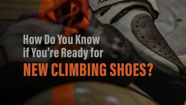 Worn climbing shoe with a scuffed rubber toe, next to an orange rope and chalk-dusted gear