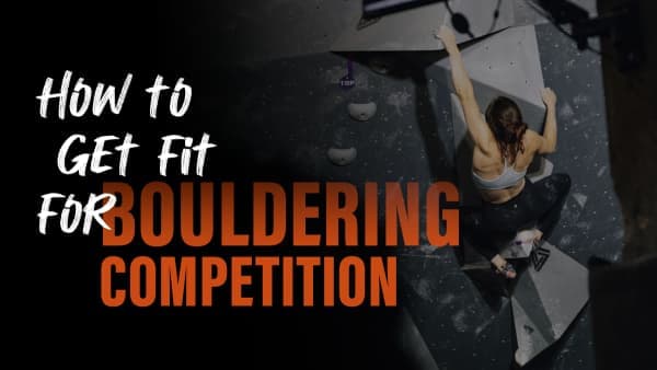 Woman in a sports bra and leggings reaches high on a dark indoor bouldering wall