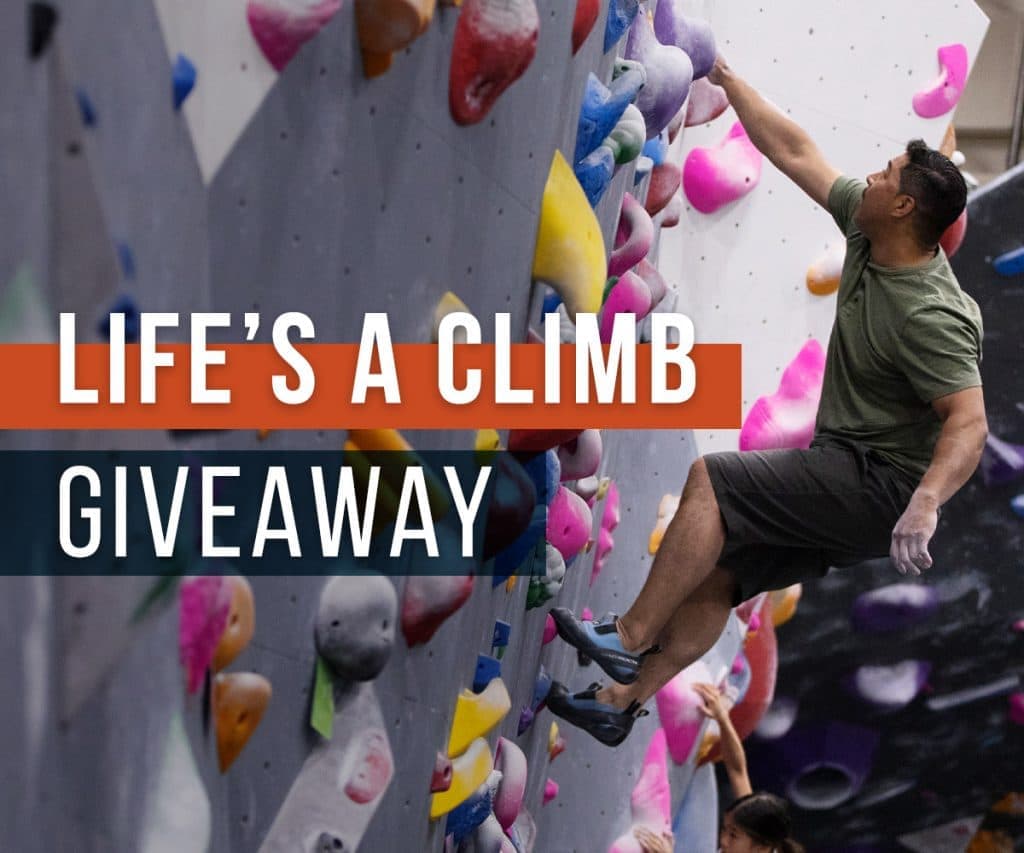 A man in a green shirt stretches for a high hold, with Life's a Climb Giveaway text overlay