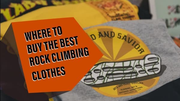 Gray graphic t-shirt with a yellow climbing hold logo lying on a table beside other shirts in a climbing shop