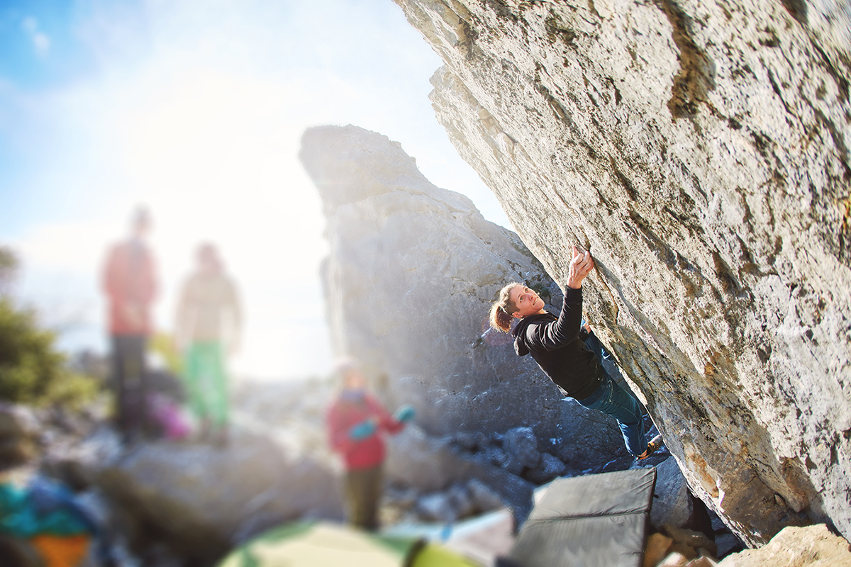 female rock climber climbs on a rocky wall. winter bouldering session